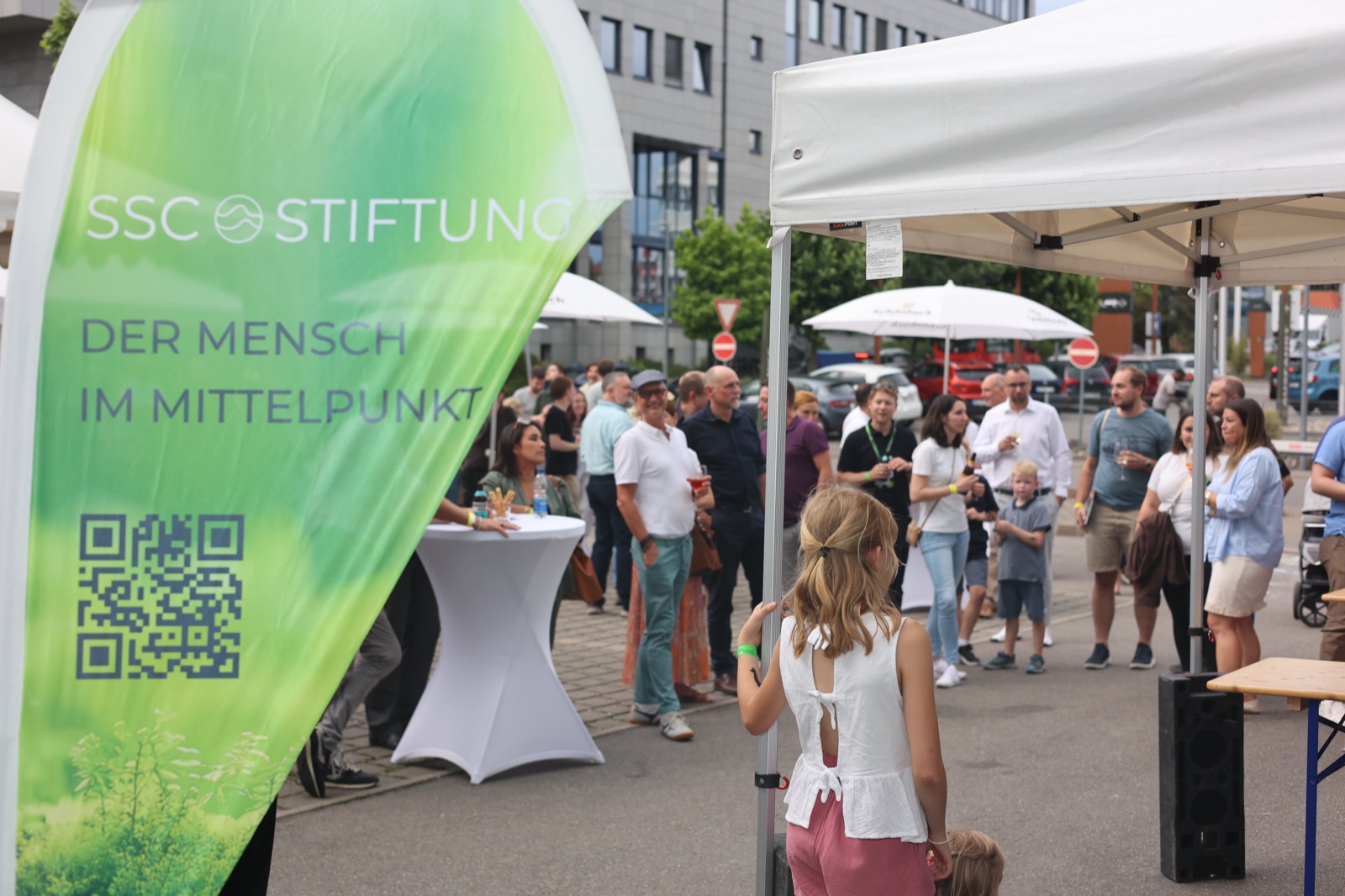 Guests at the SSC summer party next to the SSC Stiftung flag with the motto “people at the centre”